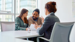 Happy couple reading terms of  agreement during  meeting with bank manager in office.